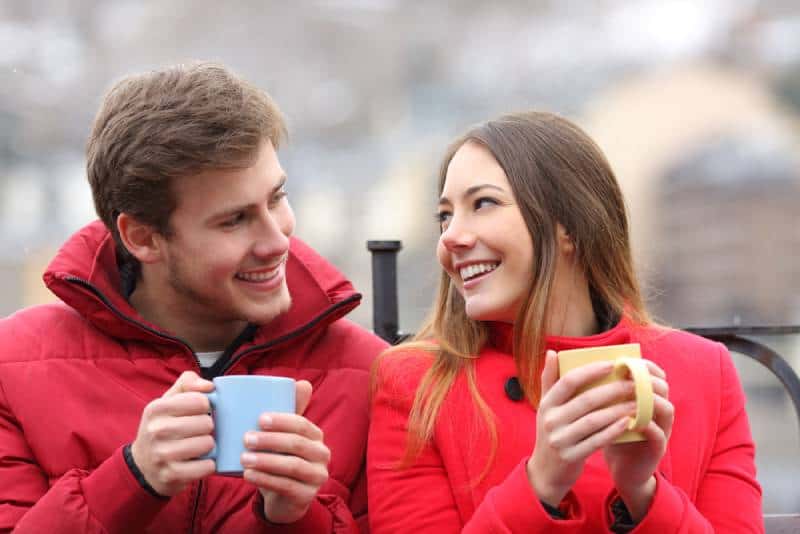 Couple parlant assis sur un banc avec un café