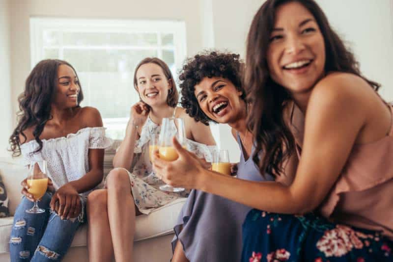 Des amies font la fête à la maison et regardent ailleurs.