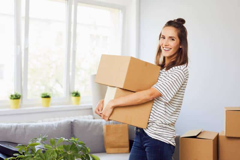 Femme de sourire retenant des boîtes dans la maison