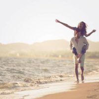 couples heureux piggybacking sur la plage