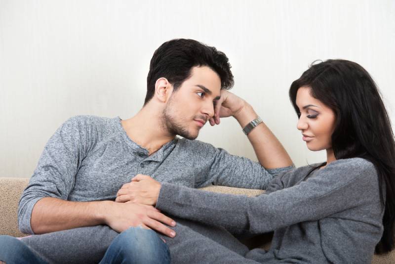 Jeune couple heureux discutant ensemble assis sur un canapé