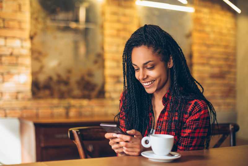 Jeune femme au café utilisant un téléphone portable