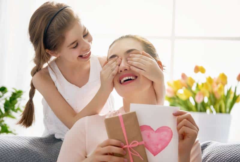 L'enfant félicite sa mère et lui offre une carte postale et un cadeau