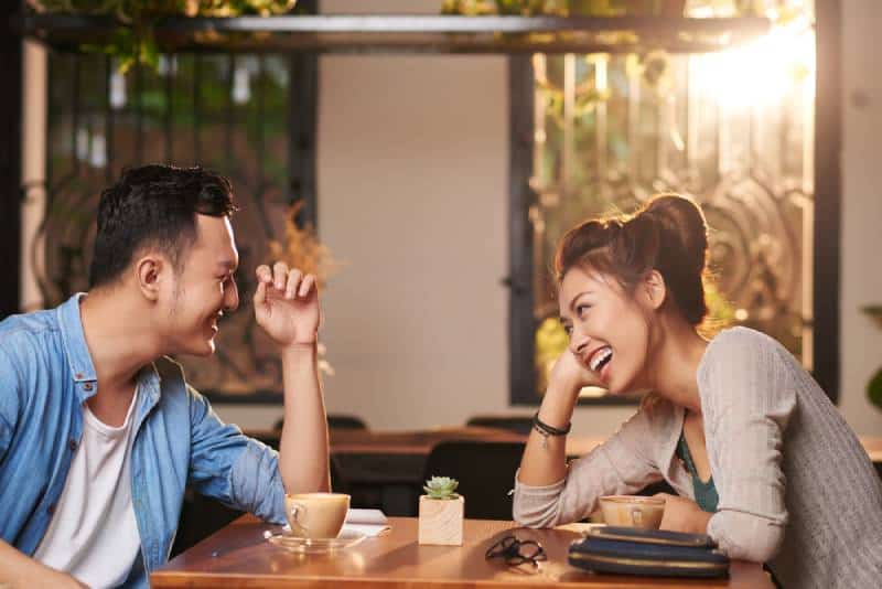 Un couple d'Asiatiques rigolant en train de sortir au café