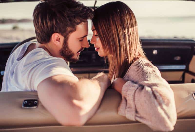 Un couple est assis dans une voiture rétro verte sur la plage