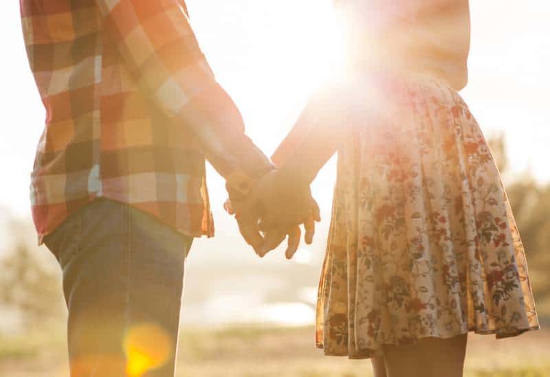 Un jeune couple d'amoureux se promène dans le regardant le coucher de soleil