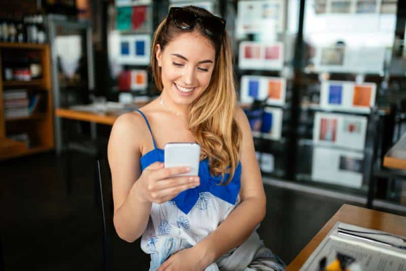 Une belle brune qui utilise son téléphone portable et envoie des SMS