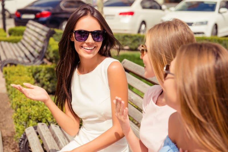 Une femme joyeuse parle à ses amis sur un banc dans un parc