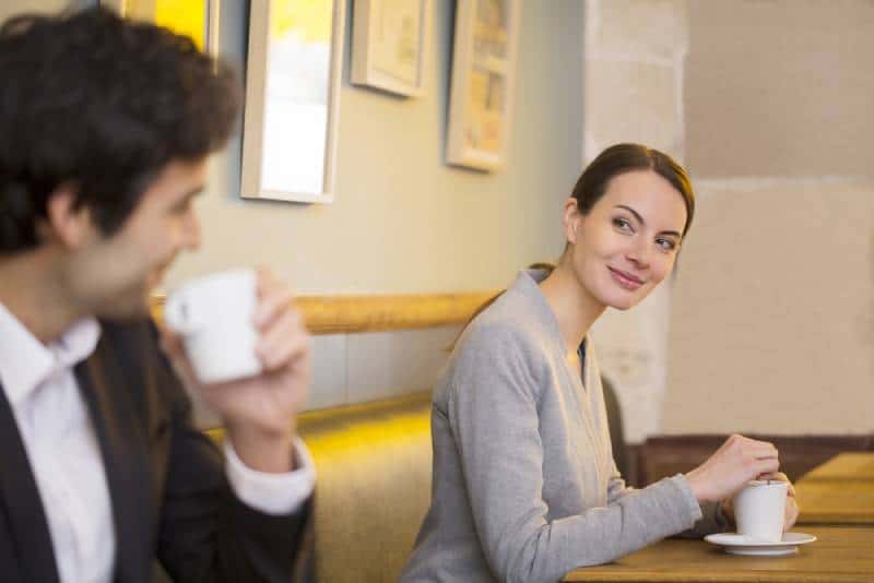 Une femme souriante regarde un homme dans un café