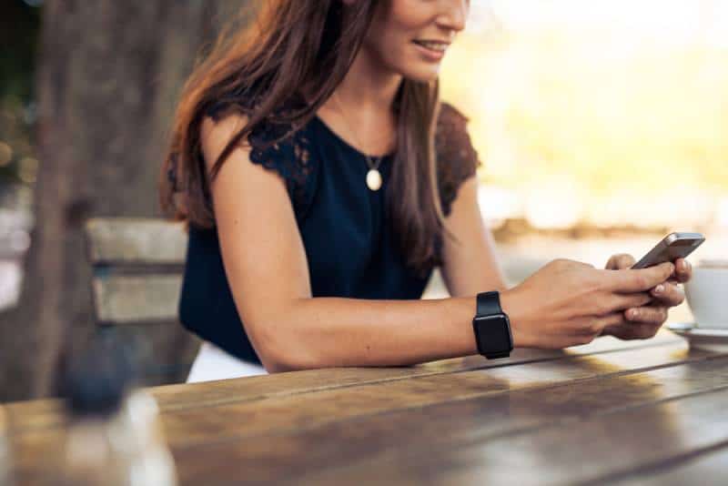 Une femme tape un message texte sur son smartphone dans un café