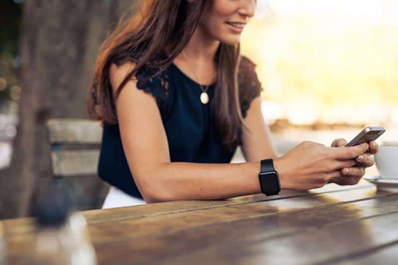 Une femme tape un message texte sur son smartphone dans un café