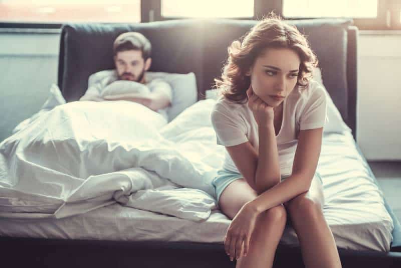 Une fille bouleversée assise sur son lit contre son petit ami