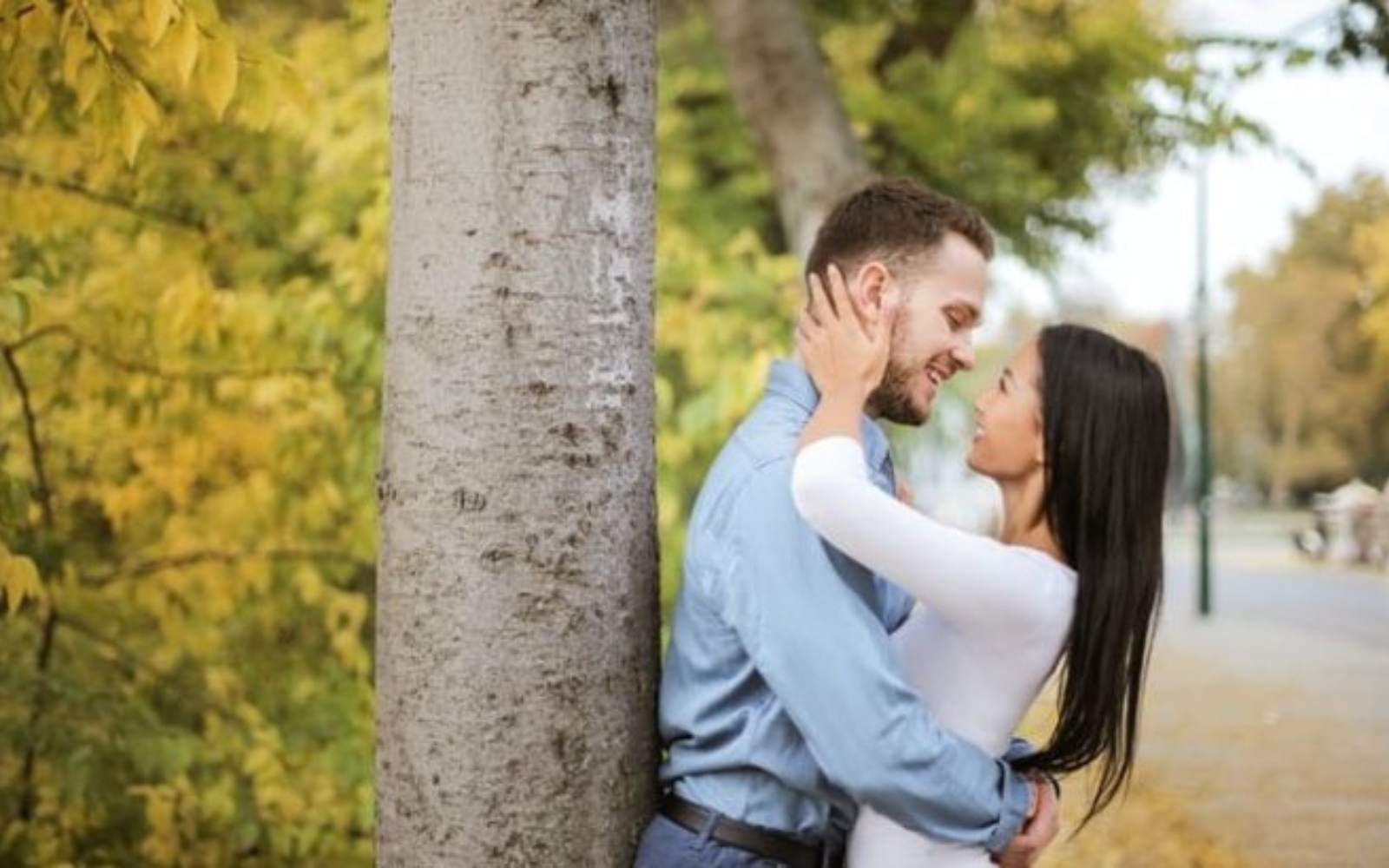 un homme et une femme sembrassant pres dun arbre