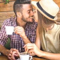 un gars qui garde une tasse de café et embrasse une fille