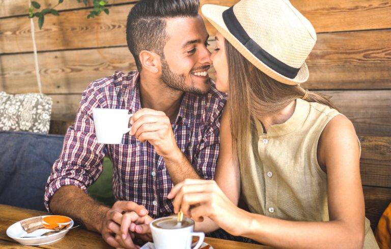 un gars qui garde une tasse de café et embrasse une fille