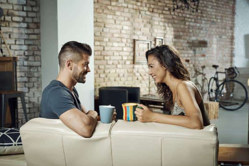 couple assis dans le salon et discutant avec un café