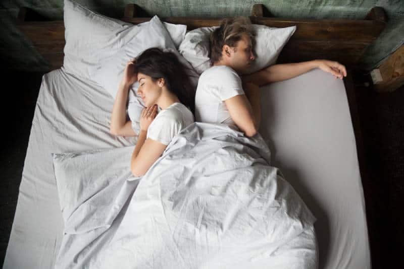couple dormant sur le lit, dos à dos dans la chambre