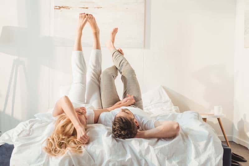 couple heureux se détendant au lit et se tenant la main le matin