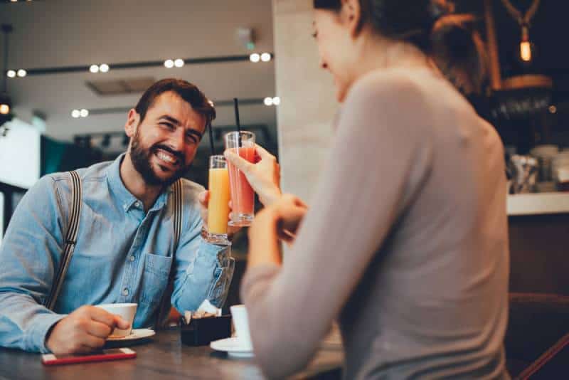 couples heureux au bar de café buvant des smoothies et encourageant