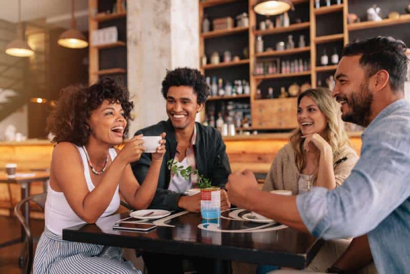 des jeunes assis dans un café et souriant.