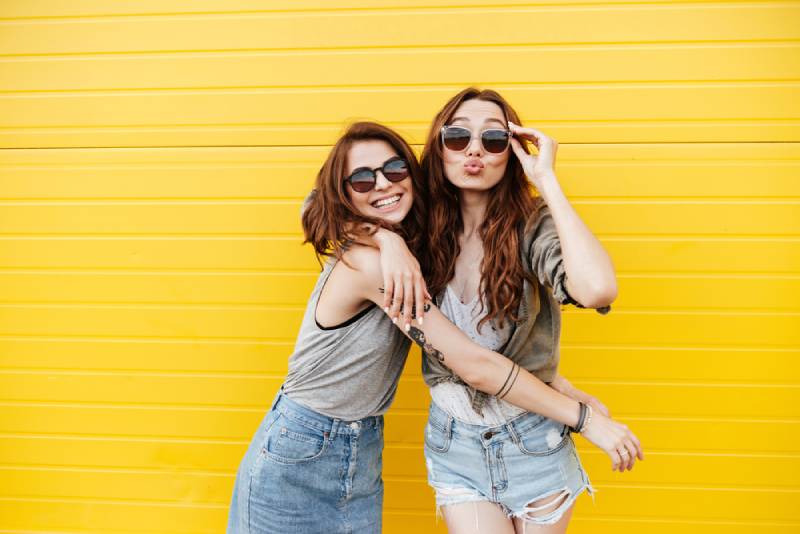 deux jeunes femmes heureuses, amies, se tenant derrière un mur