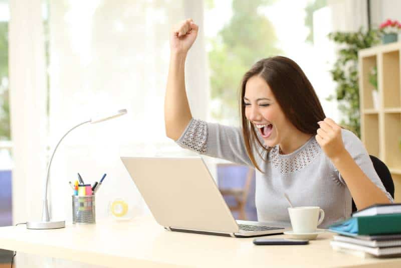 femme avec les mains et applaudir au bureau avec ordinateur portable