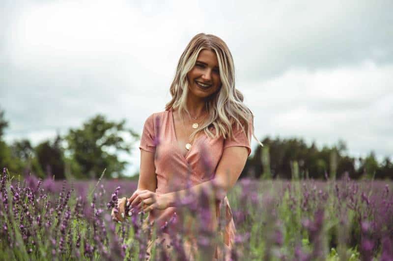 femme blonde au milieu du champ de fleurs violettes