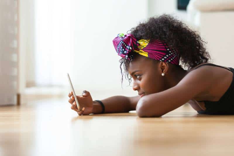 femme envoyant un message texte sur un téléphone portable alors qu'elle est allongée sur le sol