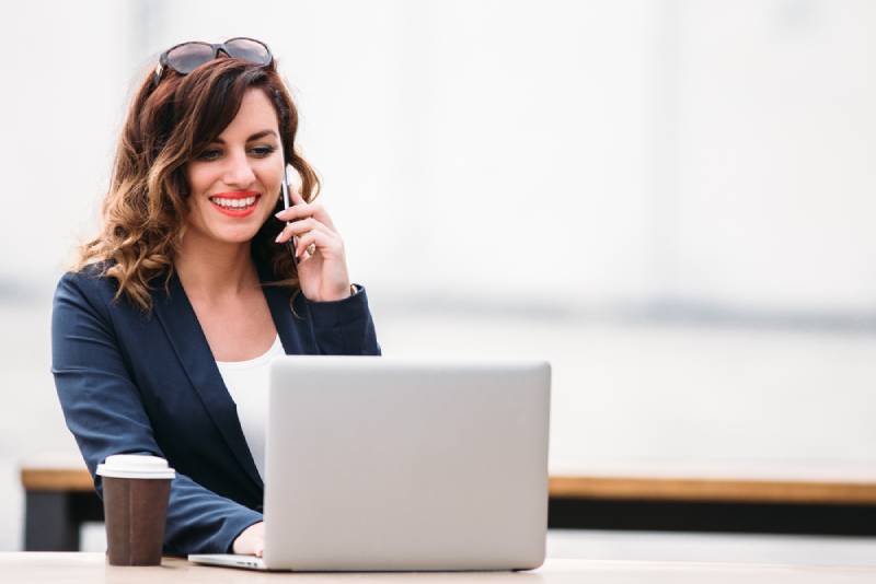 femme souriant et parlant au téléphone tout en regardant la tablette