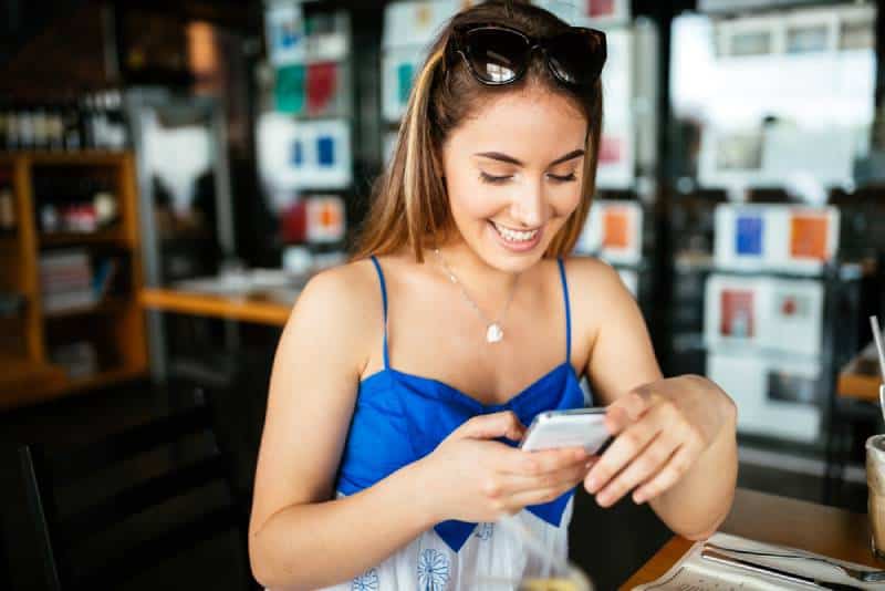femme souriante texto message café barre