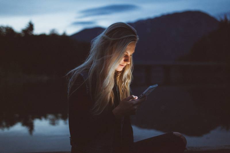 femme tapant un sms le soir au bord du lac