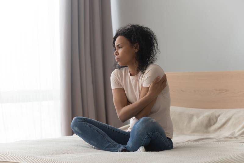 femme triste assise dans son lit, seule à la maison