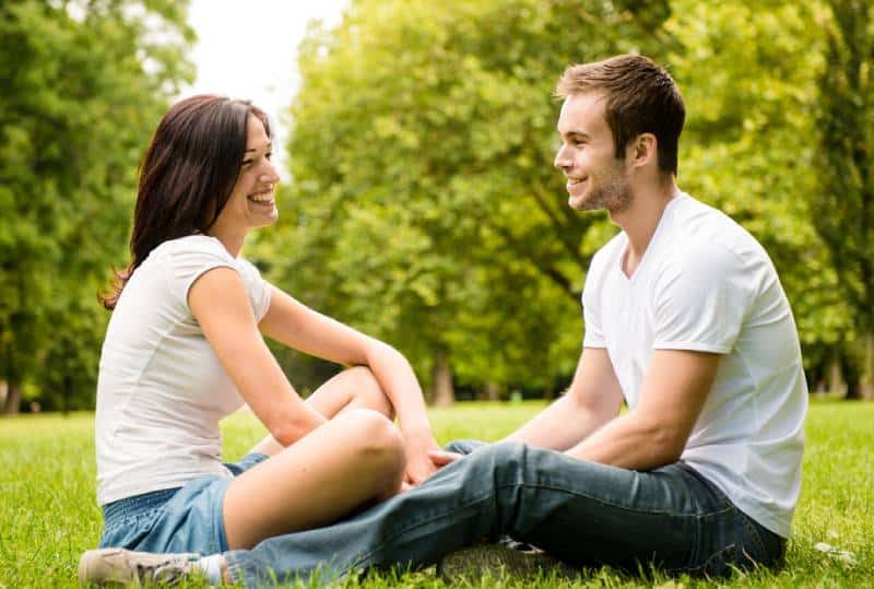 jeune couple assis sur du gras dans la nature