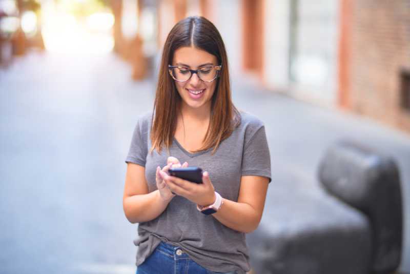 jeune femme heureuse envoyant des SMS au téléphone à l'extérieur
