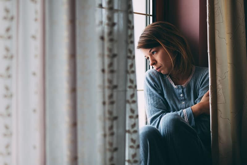 jeune femme triste par la fenêtre