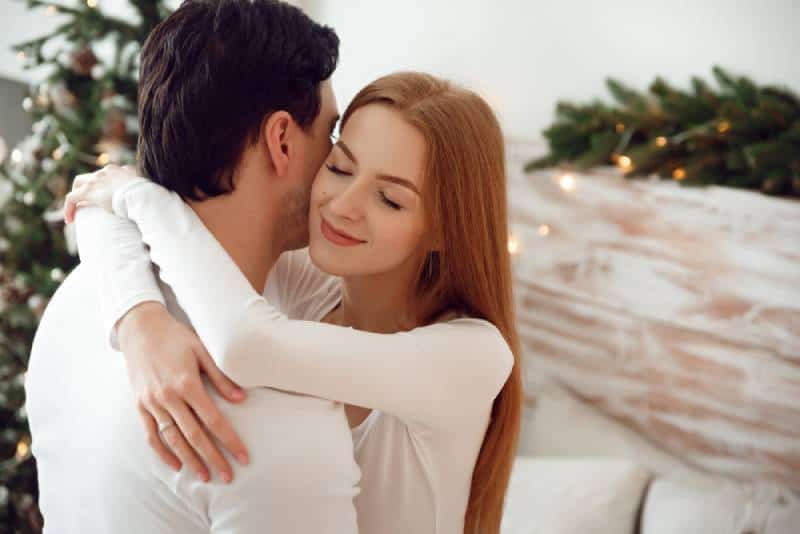 un couple s'embrasse en amoureux près de l'arbre de Noël