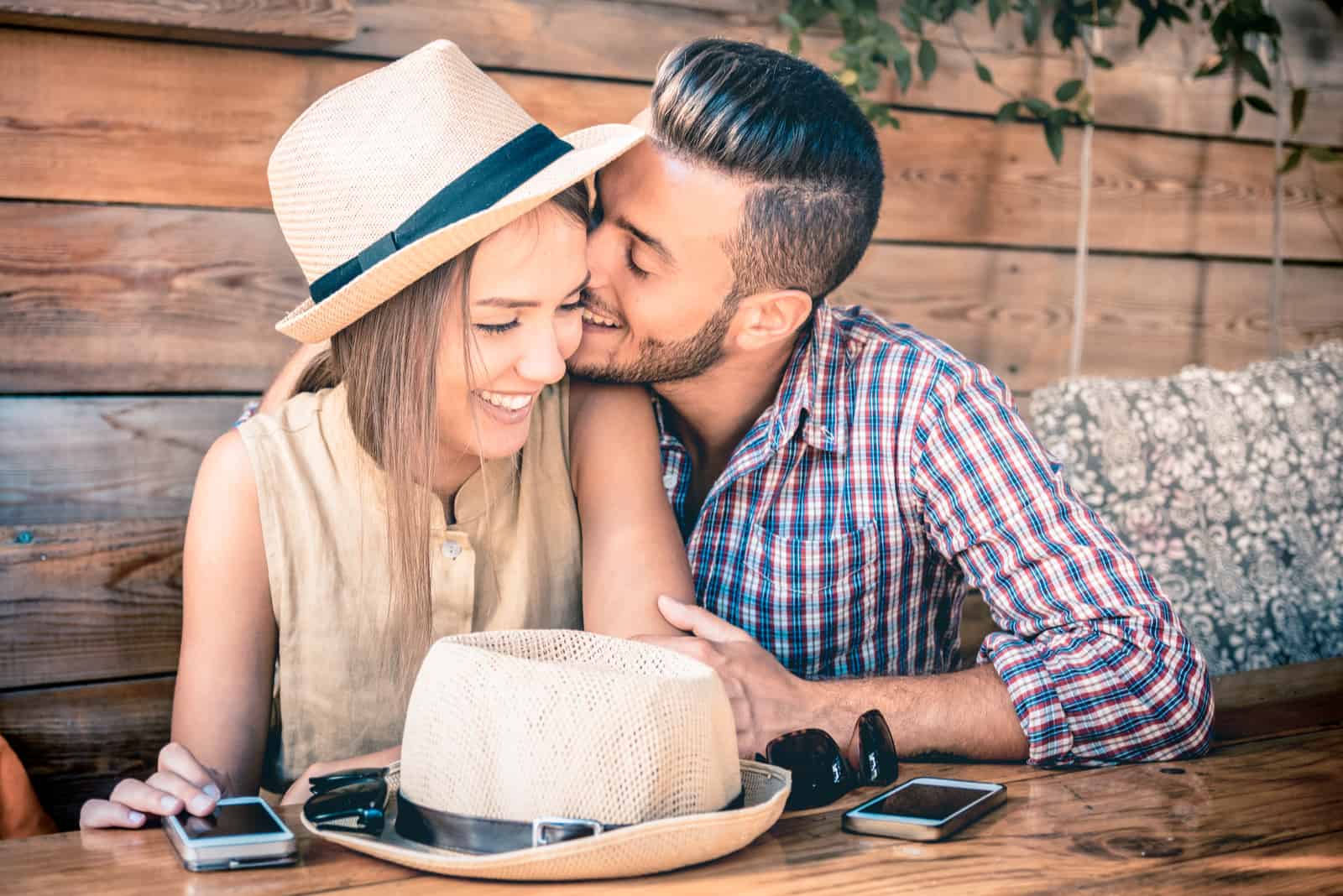 un homme souriant embrasse une femme avec un chapeau