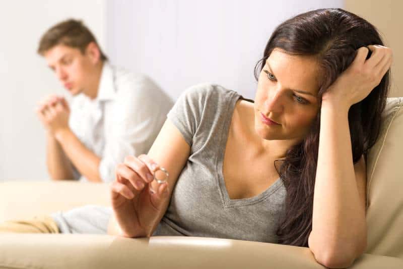 une femme en colère qui regarde sa bague alors que son mari est bienveillant