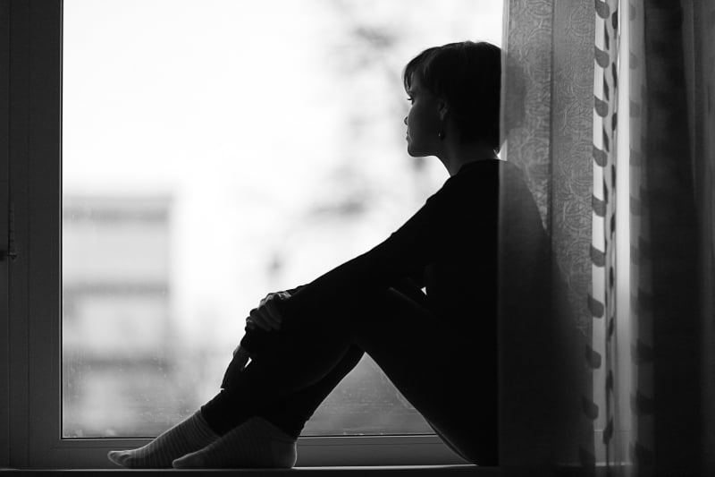une fille solitaire est assise près de la fenêtre