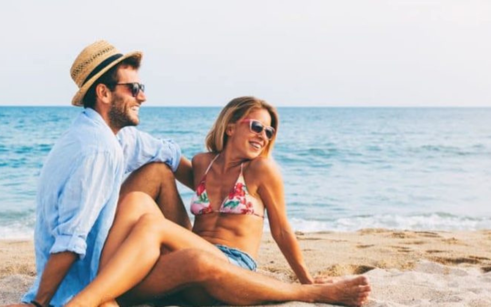 un homme et une femme sont assis sur la plage