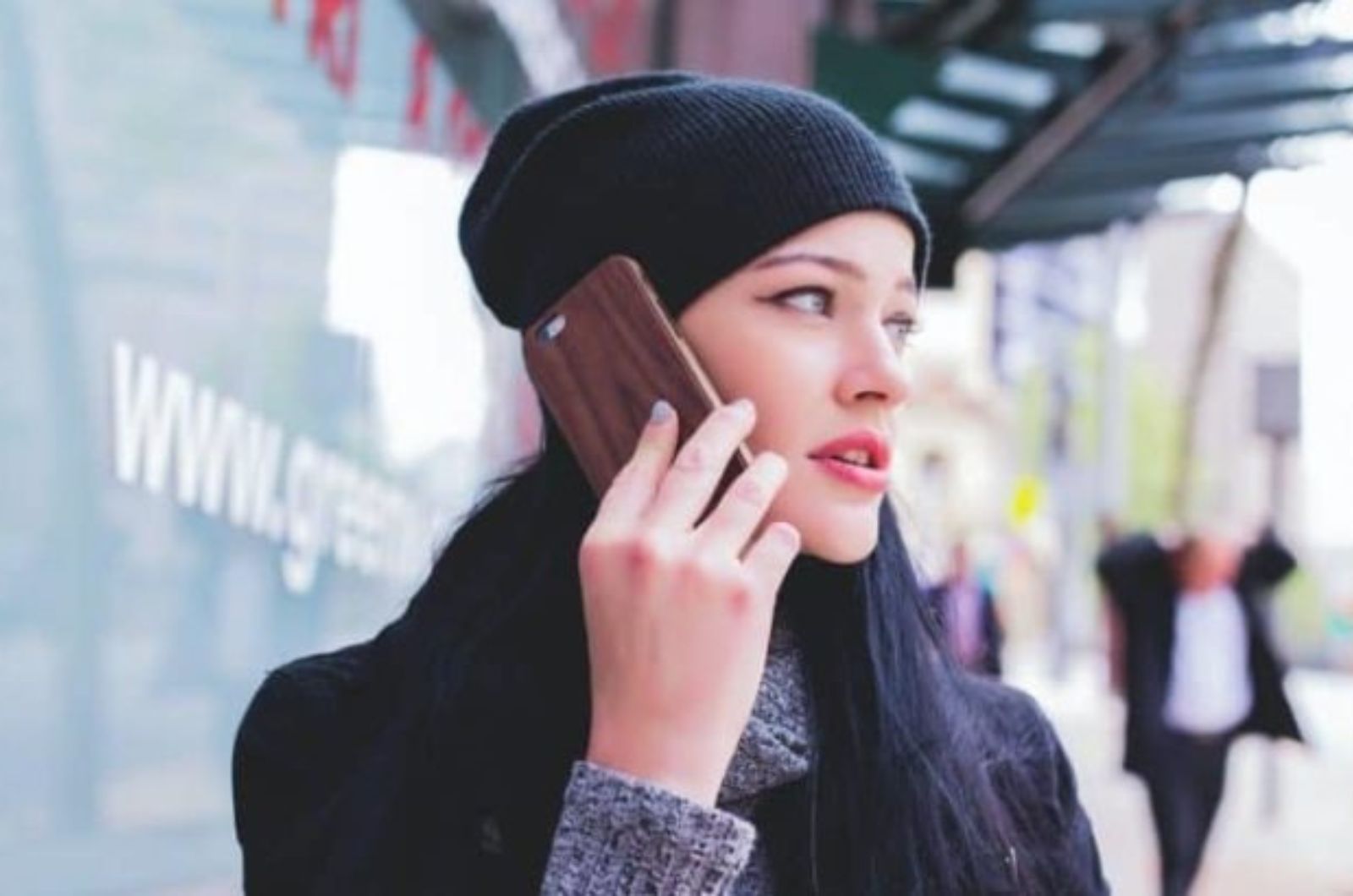 une femme avec un chapeau sur la tete est au telephone