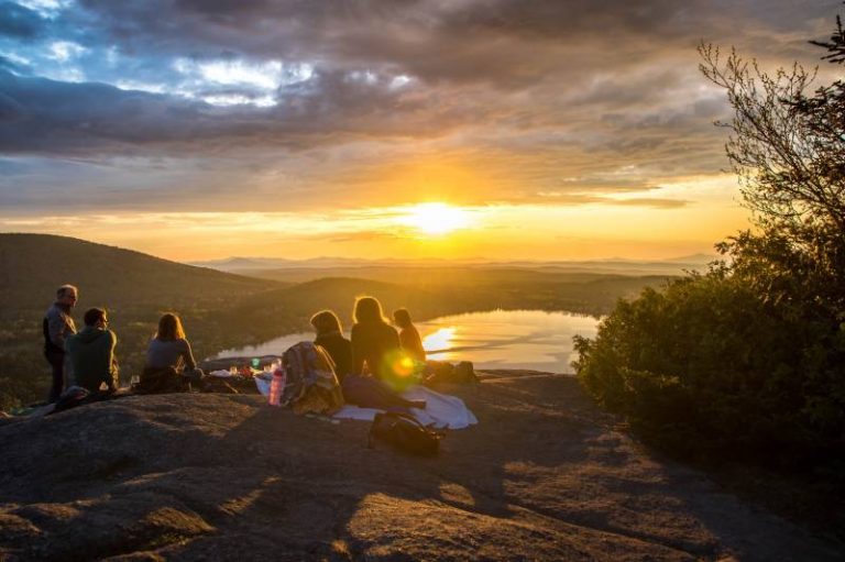 un groupe de personnes se dirigeant vers le soleil couchant