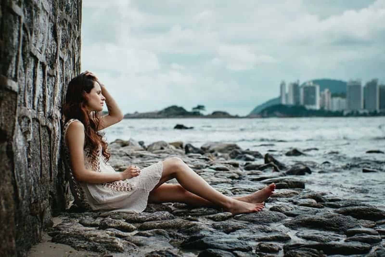 une femme triste assise sur un rocher