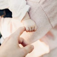 bébé tenant le doigt de sa mère