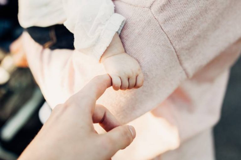 bébé tenant le doigt de sa mère