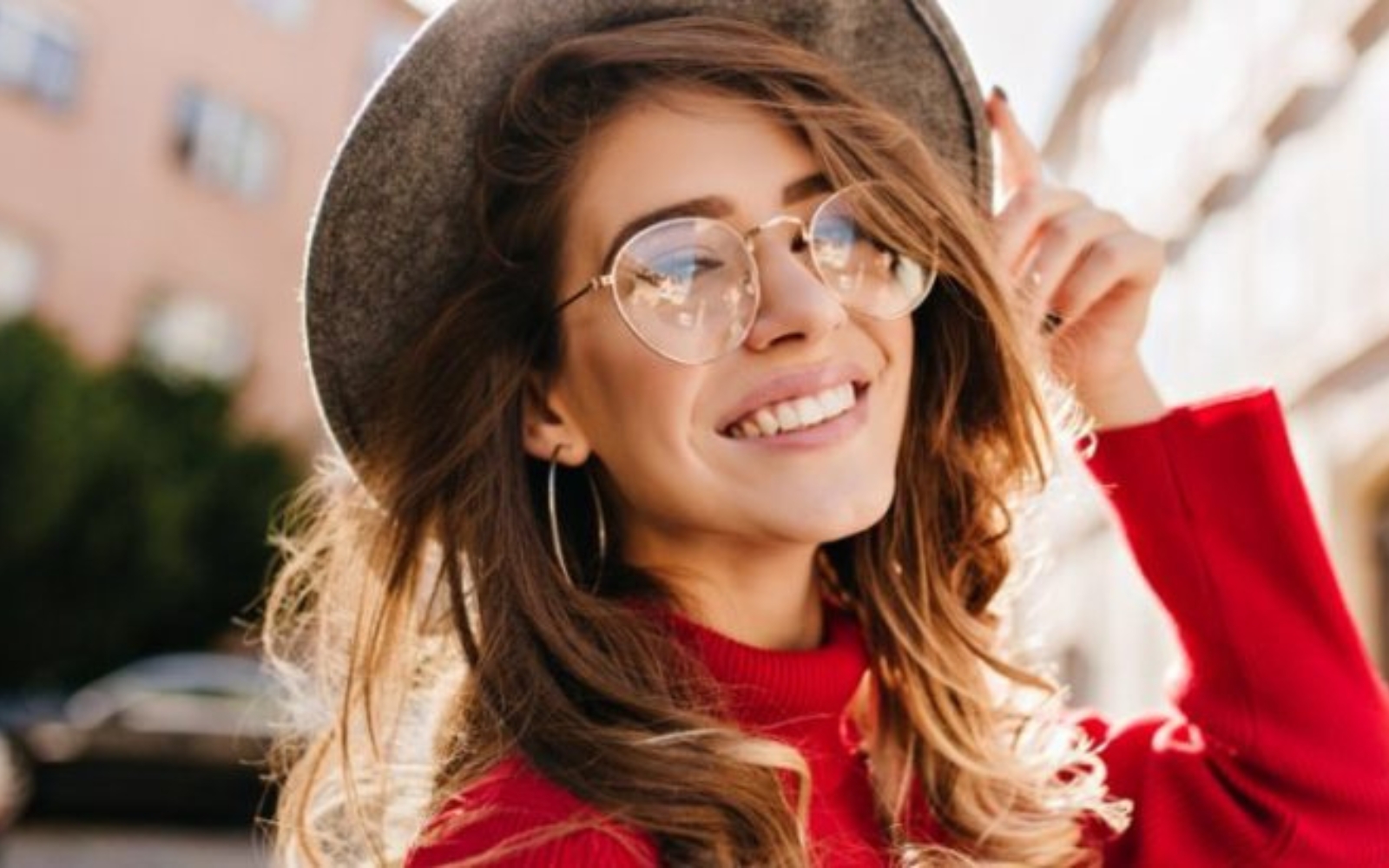 une femme avec des lunettes et un chapeau rit