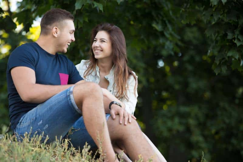 Portrait d'un beau jeune couple amoureux et joyeux, en tenue décontractée, se détendant dans un parc