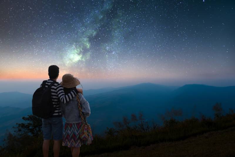Un couple regarde les étoiles dans le ciel et la voie lactée lors d'une nuit romantique
