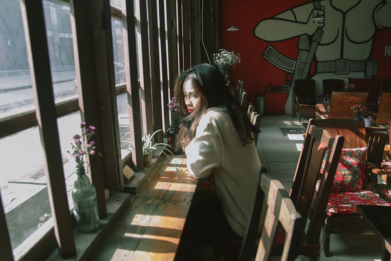 Une femme attentionnée assise à la fenêtre d'un café