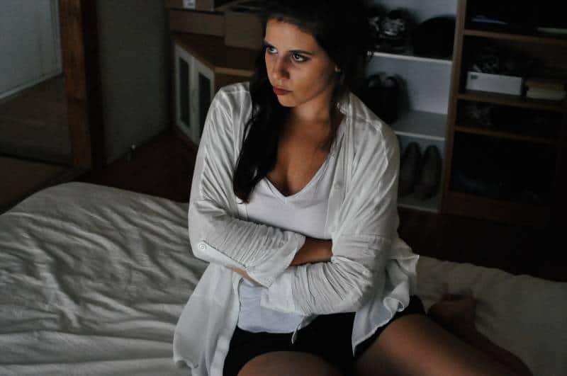 Une femme inquiète, assise dans sa chambre, à la maison